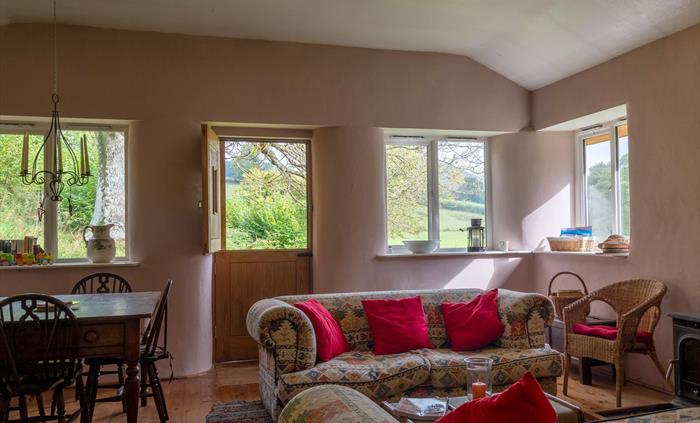 Large sitting room with dining table, wood burner, French doors to veranda with far reaching views.